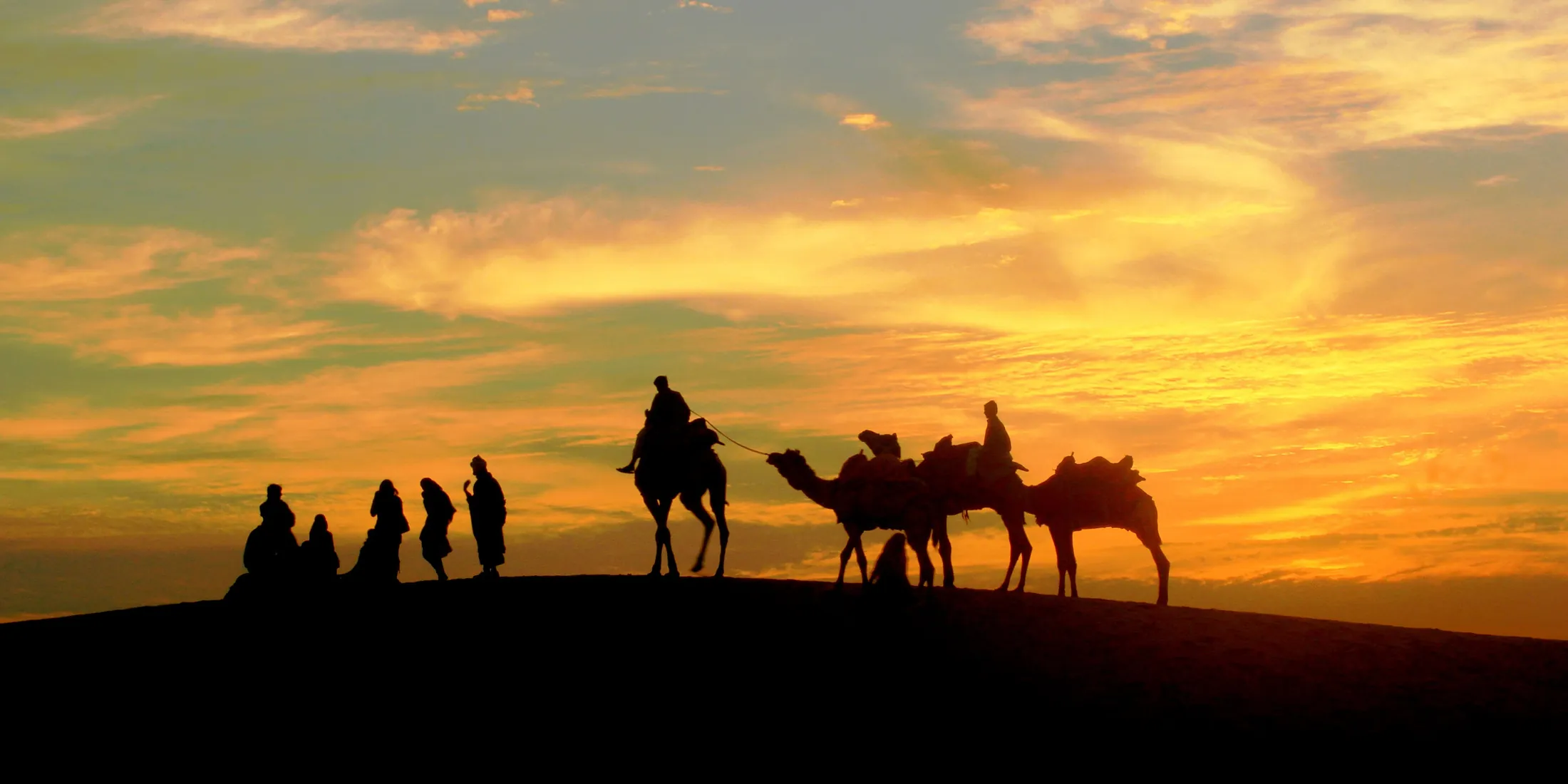 A camel caravan crossing the dunes at sunset near Jaisalmer